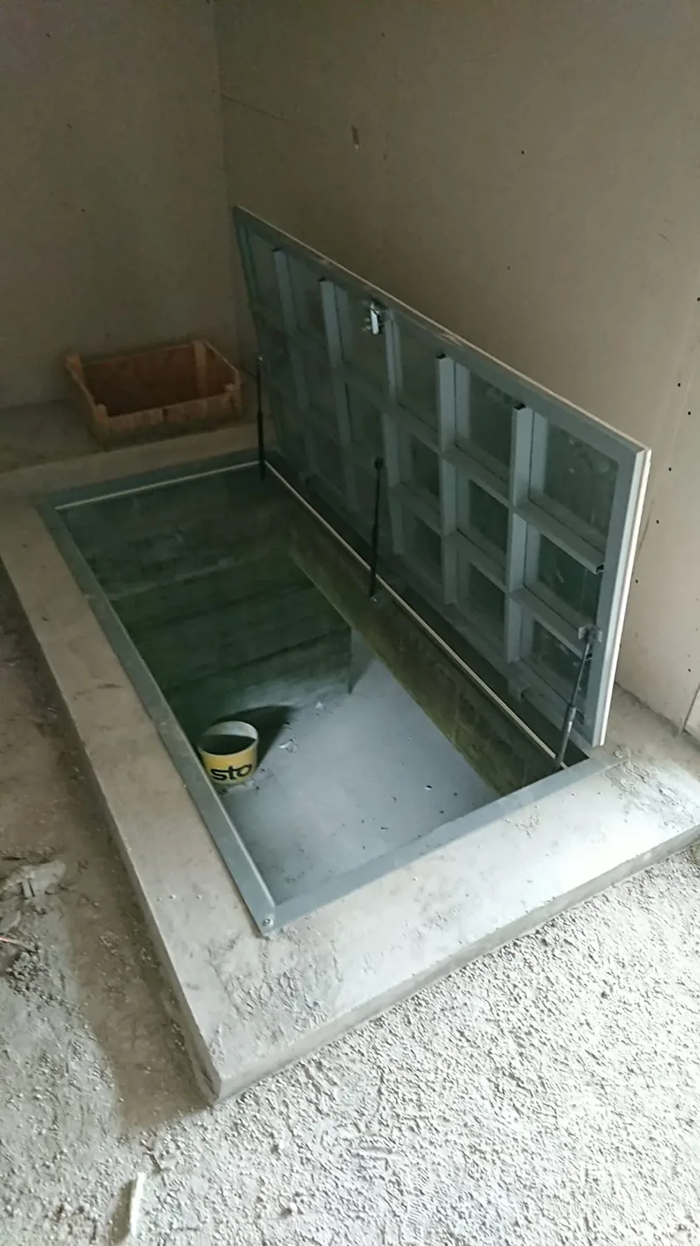 Iekštelpu grīdas lūka ar atvērtu rāmi